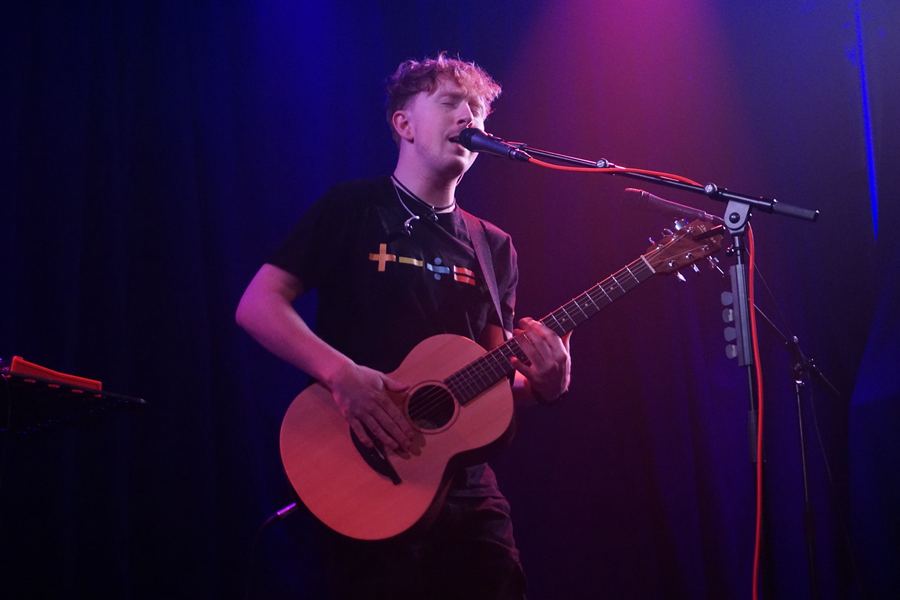 Matt Keddie hitting the guitar body for a percussive beat while singing